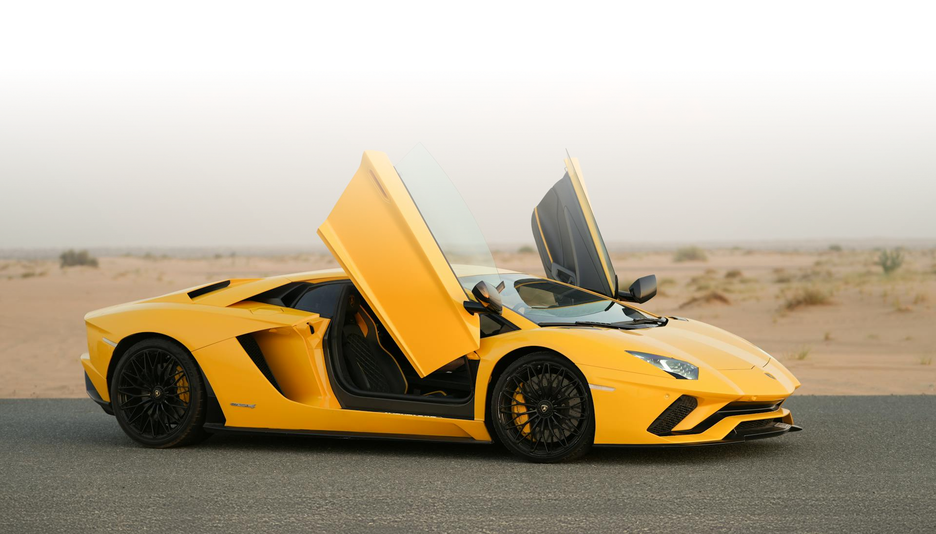 Żółte Lamborghini Aventador z otwartymi drzwiami nożycowymi stoi na pustynnej drodze