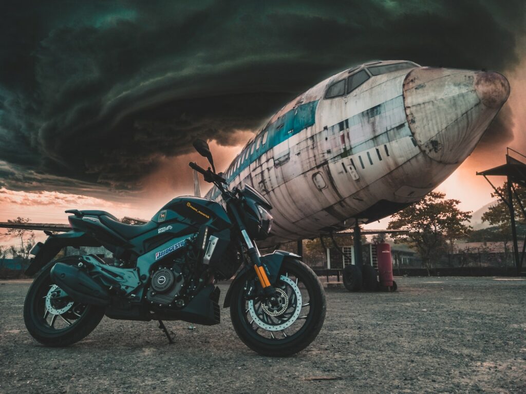 Motocykl stoi przed opuszczonym samolotem pod dramatycznym, burzowym niebem
