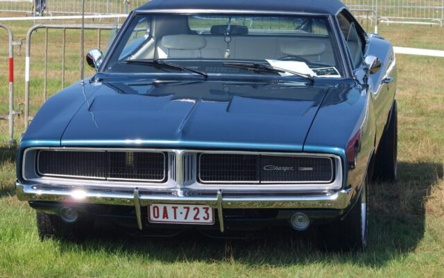 Klasyczny Dodge Charger zaparkowany na trawie podczas plenerowego zlotu aut