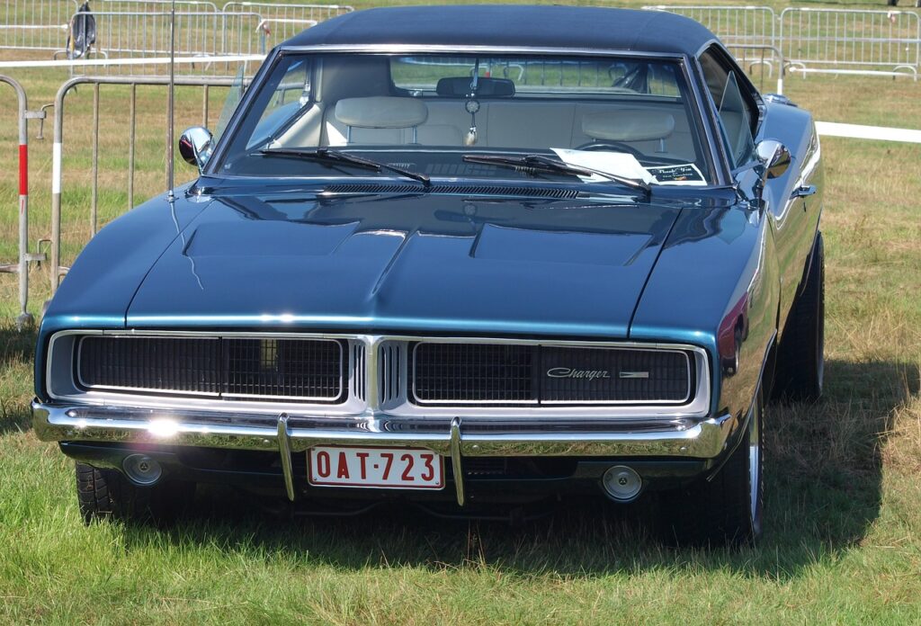 Klasyczny Dodge Charger zaparkowany na trawie podczas plenerowego zlotu aut