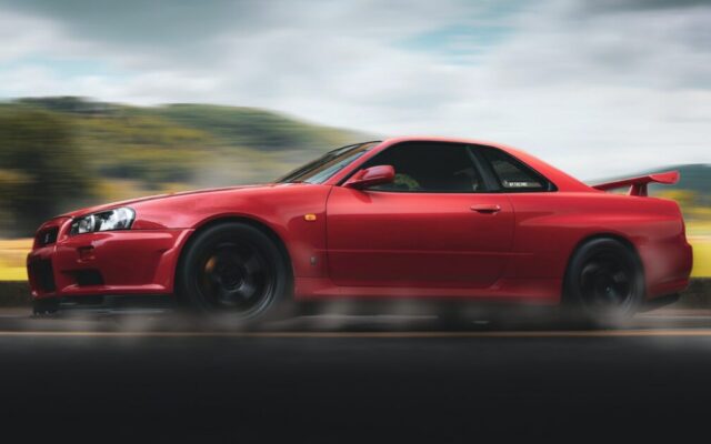Czerwony Nissan Skyline GT-R jedzie szybko po drodze, z rozmytym tłem i ruchem kół