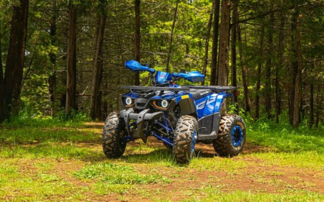 Niebieski quad terenowy stoi na leśnej ścieżce wśród drzew i zieleni