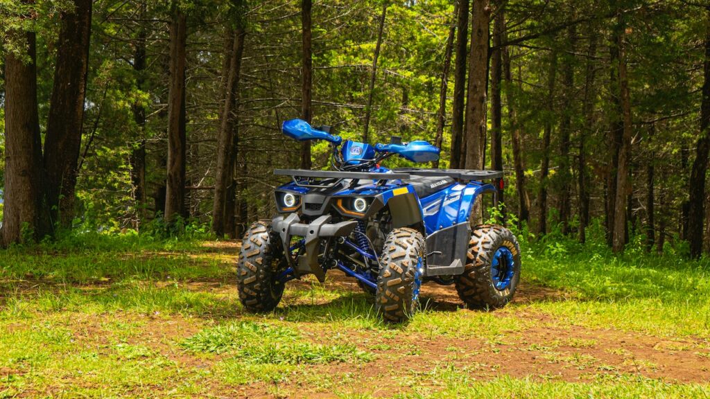 Niebieski quad terenowy stoi na leśnej ścieżce wśród drzew i zieleni