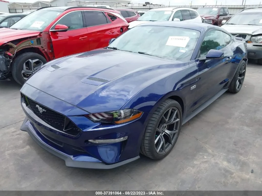 Niebieski Ford Mustang GT - ujęcie 3/4 z przodu po lewej, parking aukcyjny.