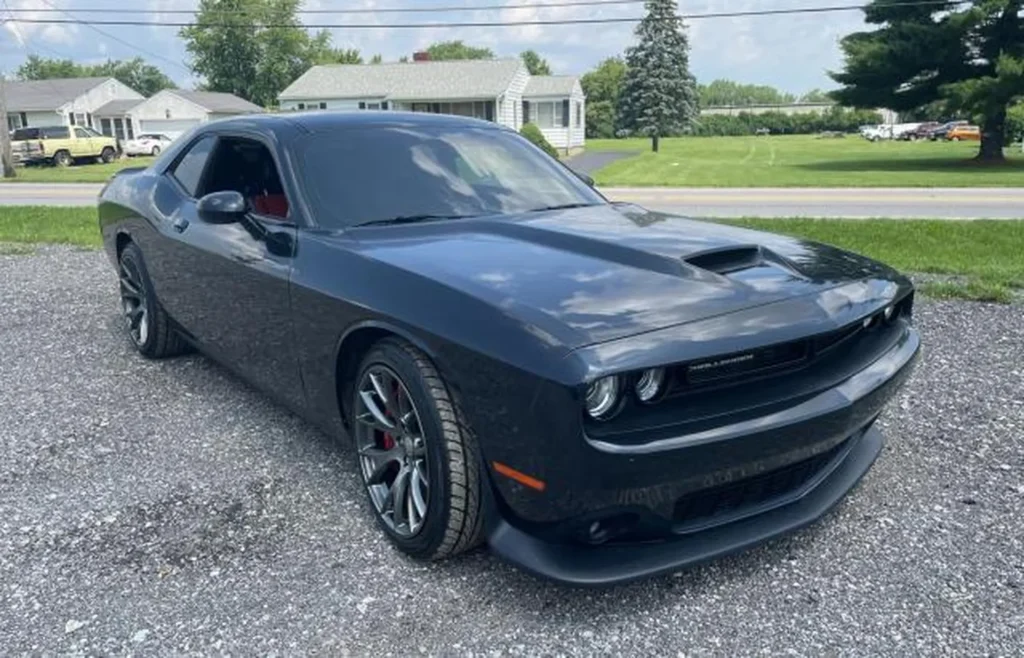 Czarny Dodge Challenger SRT 392 - ujęcie 3/4 z przodu z lewej, maska z wlotem powietrza, sportowe felgi, przyciemnione szyby.