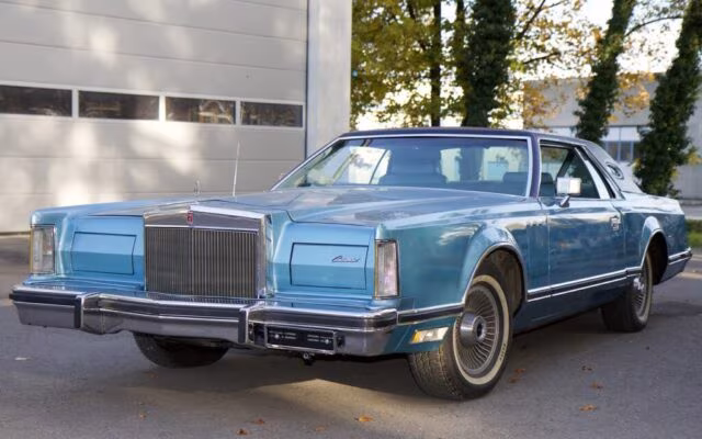 Niebieski klasyczny Lincoln Continental coupe zaparkowany przed garażem w świetle dnia