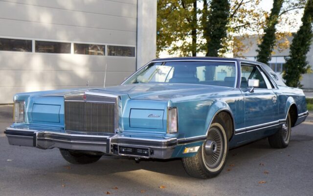 Niebieski klasyczny Lincoln Continental coupe zaparkowany przed garażem w świetle dnia