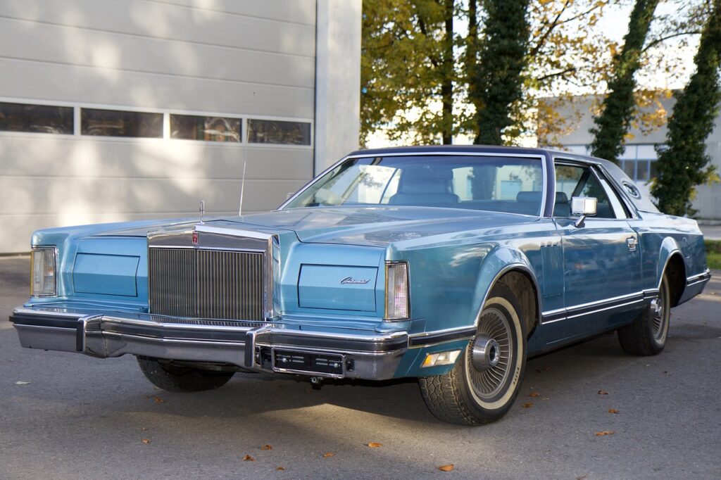 Niebieski klasyczny Lincoln Continental coupe zaparkowany przed garażem w świetle dnia