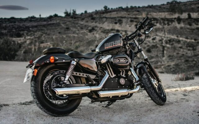 Czarny motocykl cruiser Harley-Davidson stoi na pustynnej drodze na tle skalistych wzgórz