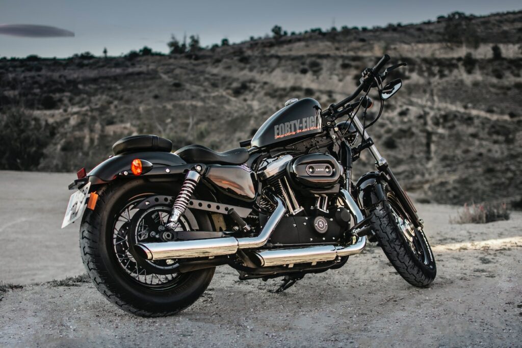 Czarny motocykl cruiser Harley-Davidson stoi na pustynnej drodze na tle skalistych wzgórz