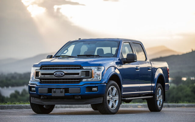 Niebieski pickup Ford F-150 zaparkowany na drodze z górskim krajobrazem w tle