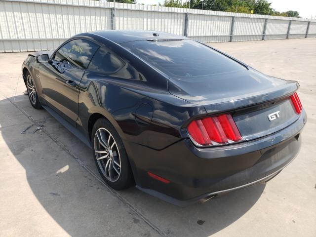Czarny Ford Mustang GT, tył-lewy rzut, zaparkowany na betonie, seryjne felgi.