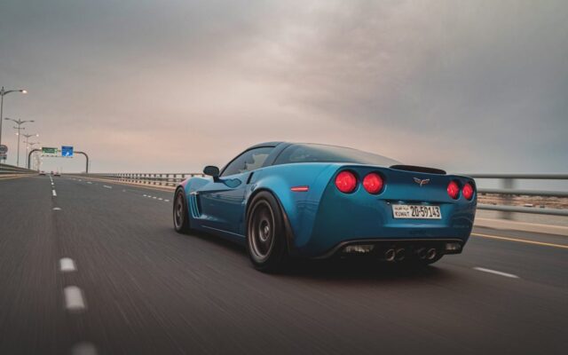 Niebieski Chevrolet Corvette jedzie autostradą o zmierzchu, widok od tyłu z rozmytym ruchem