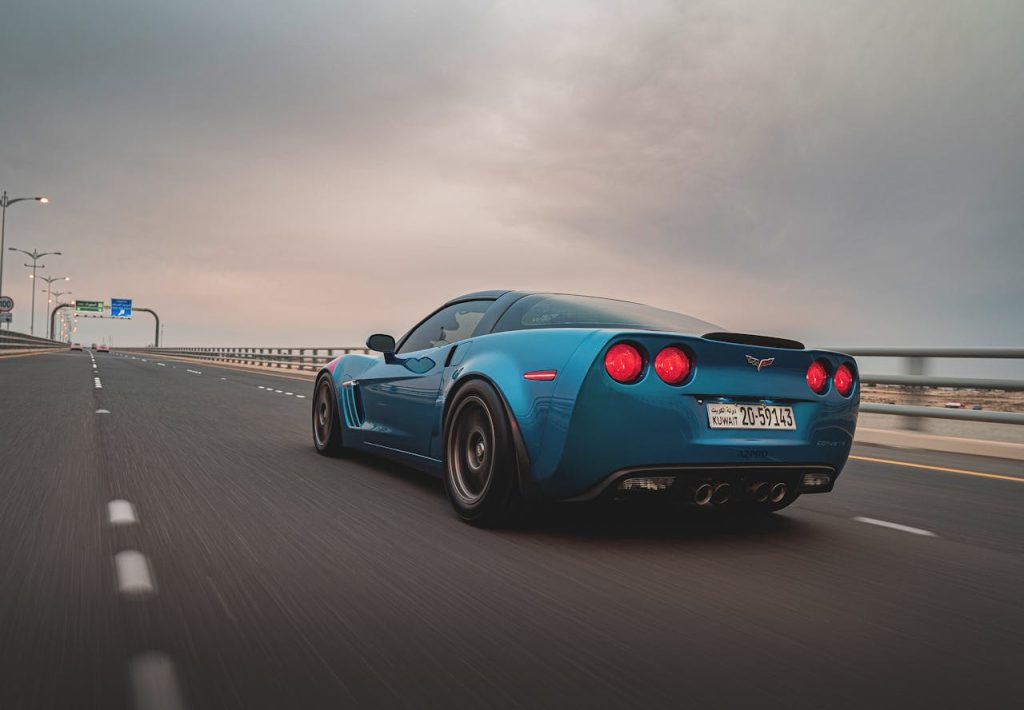Niebieski Chevrolet Corvette jedzie autostradą o zmierzchu, widok od tyłu z rozmytym ruchem