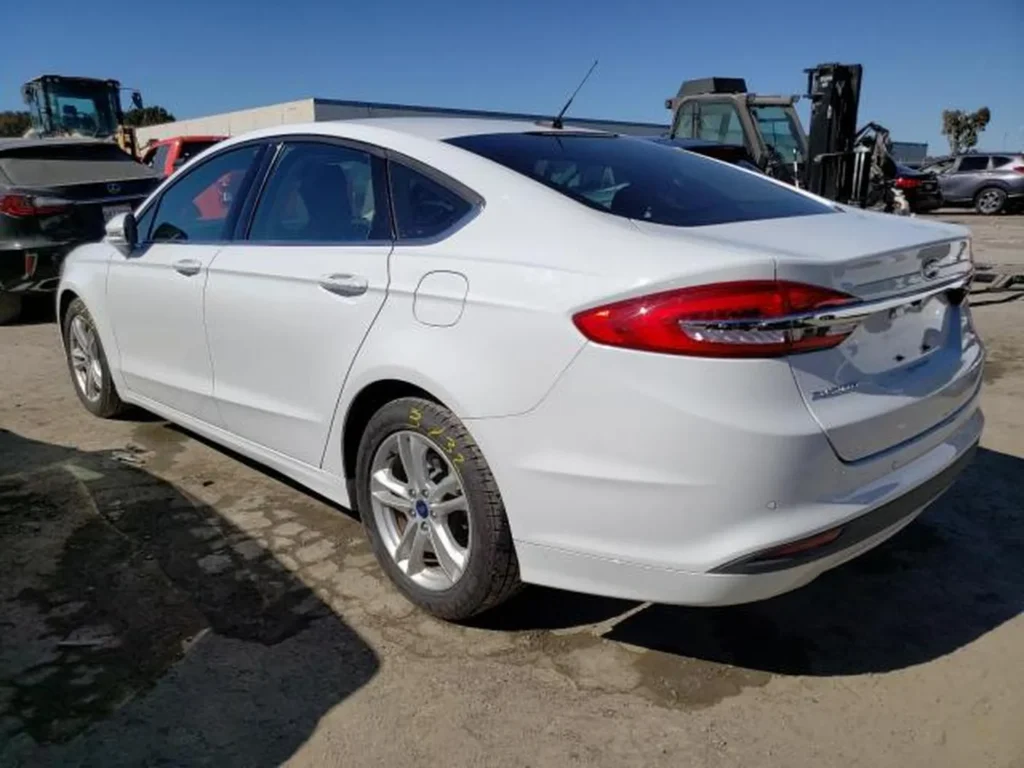 Biały Ford Fusion – tył/prawy bok, emblemat GT-Line znikomy; światła tylne LED, parking przy koparce.