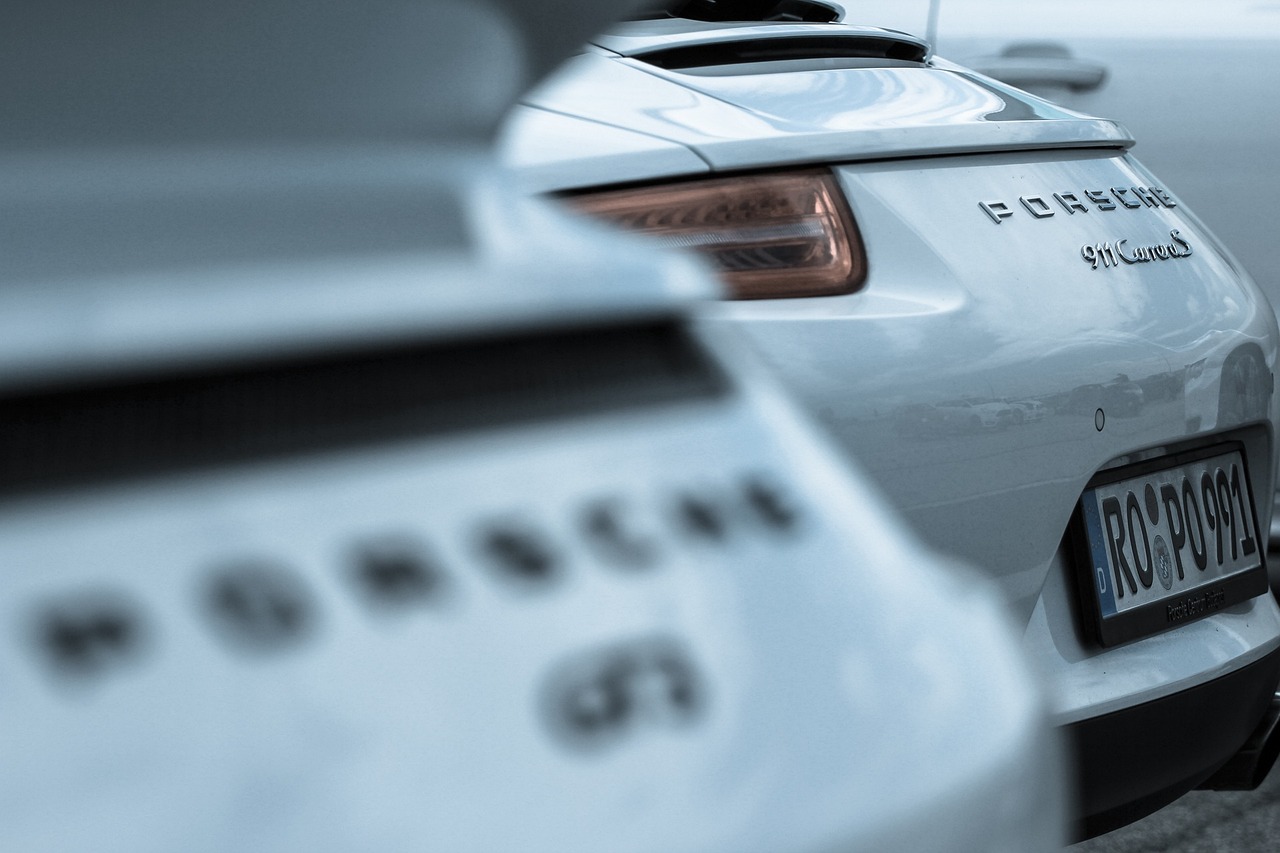 Zbliżenie na tył dwóch modeli Porsche 911 – GT3 i Carrera, z subtelnym rozmyciem pierwszego planu, podkreślającym detale oznaczeń i elegancję sportowych sylwetek.
