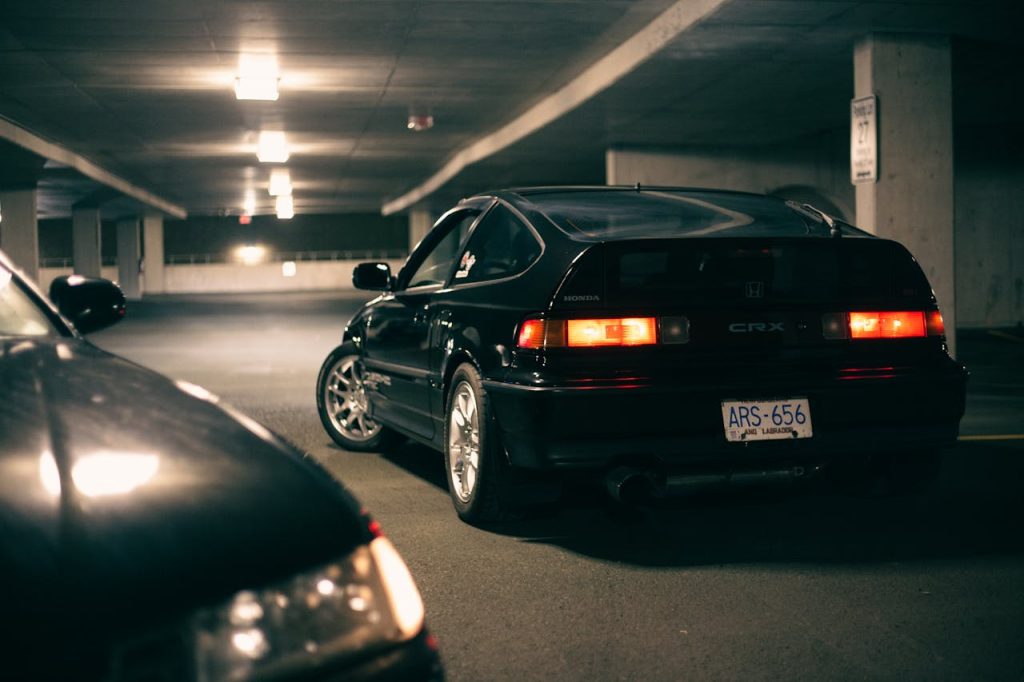 Czarna Honda CRX z włączonymi tylnymi światłami w podziemnym parkingu nocą