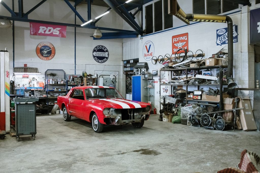 Czerwony klasyczny Mustang w trakcie renowacji w warsztacie samochodowym pełnym części i narzędzi