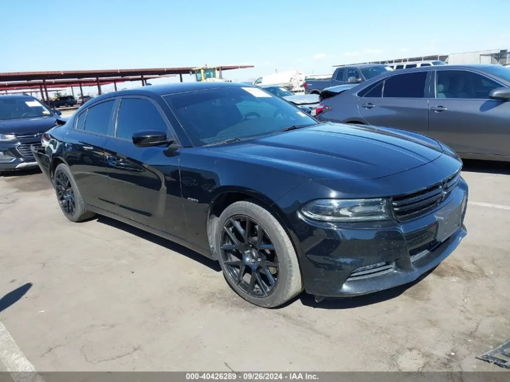 Czarny Dodge Charger sedan z czarnymi felgami, ujęcie z prawego przodu na placu aukcyjnym.