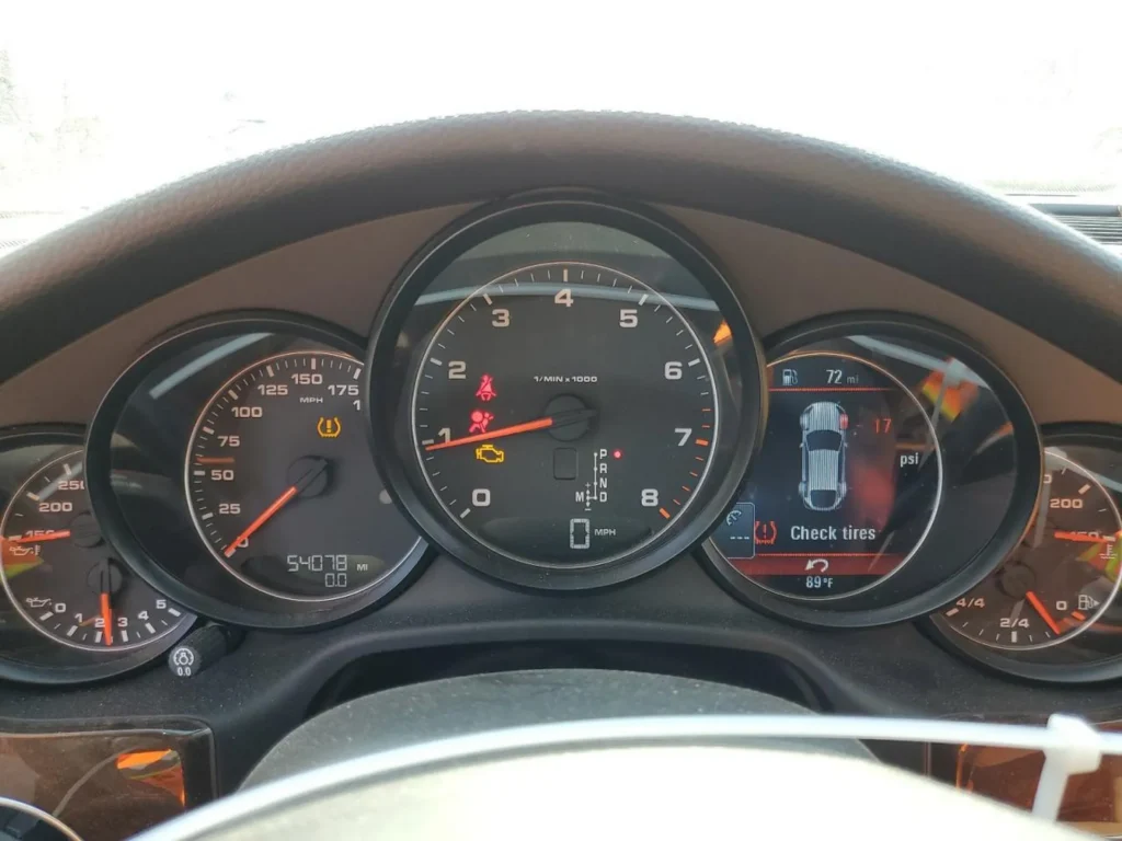 Zestaw zegarów; obrotomierz centralny, komunikat „Check tires”, przebieg ok. 54 078 mil, temp. 89°F.