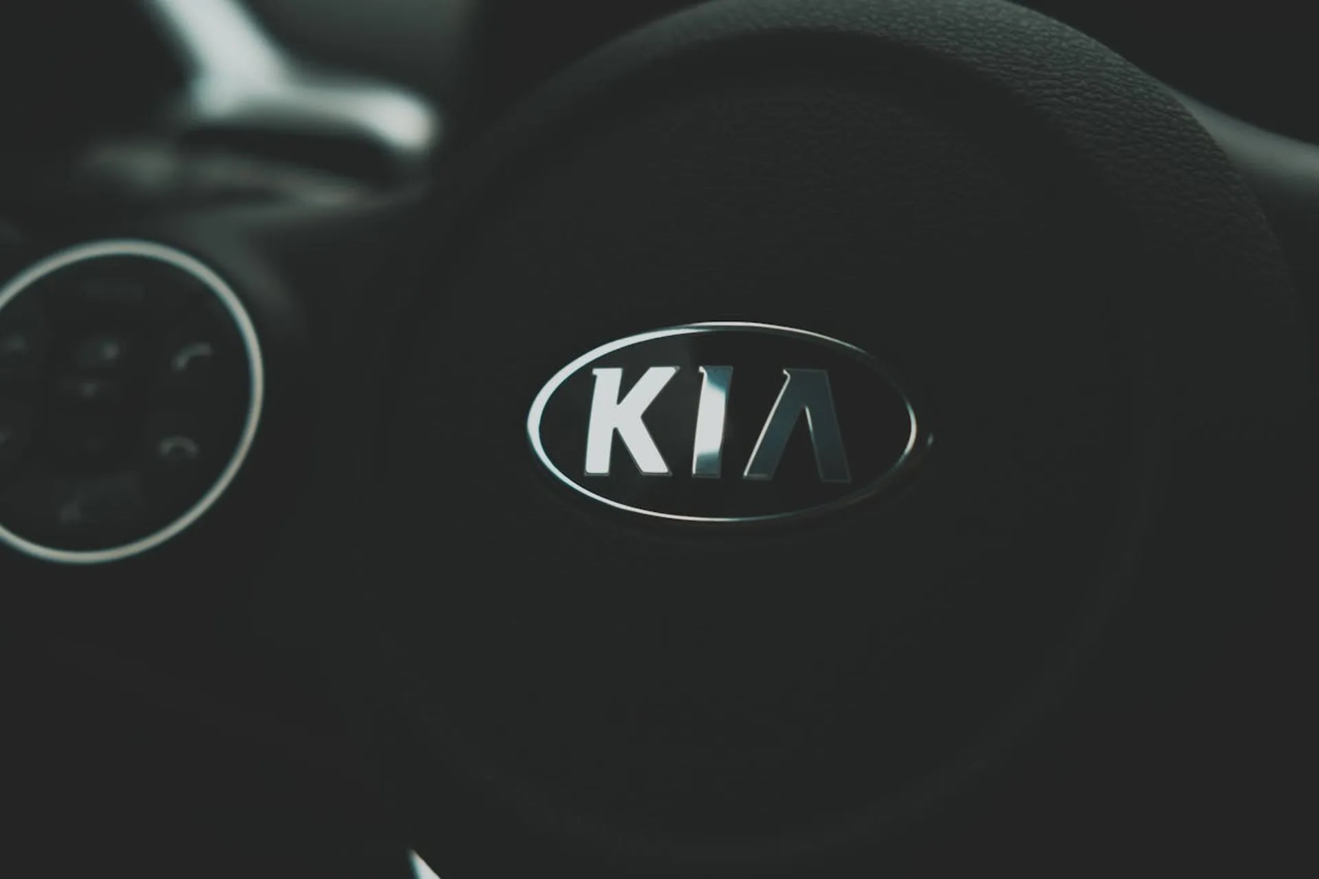 Zbliżenie na logo KIA na kierownicy w ciemnym wnętrzu auta