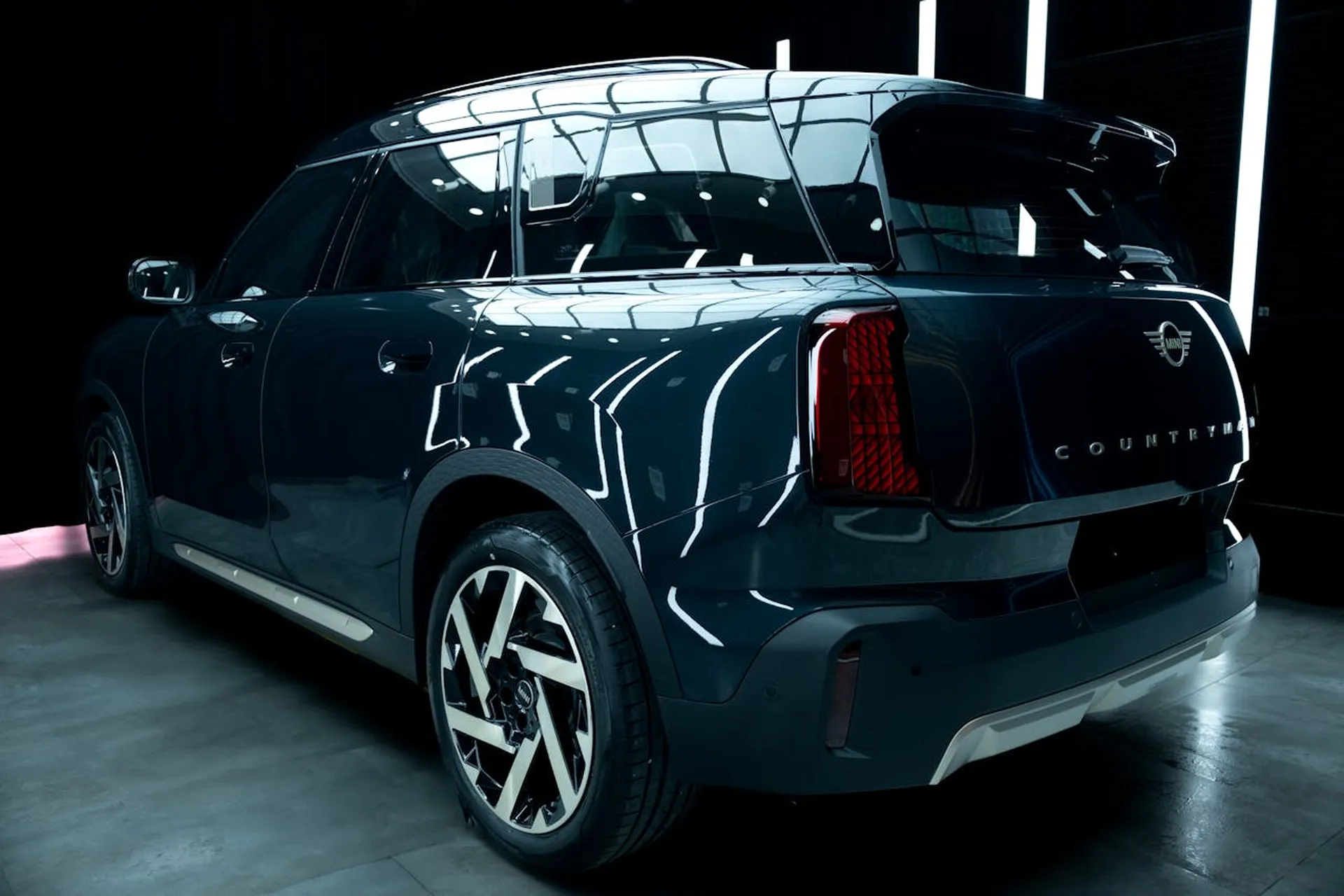 Tył ciemnoniebieskiego Mini Countryman prezentowany w oświetlonym studio samochodowym