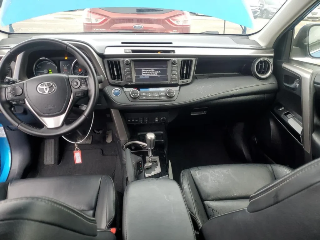 Kokpit Toyota RAV4: deska rozdzielcza z ekranem multimediów, automatyczna skrzynia biegów, czarne wykończenie.