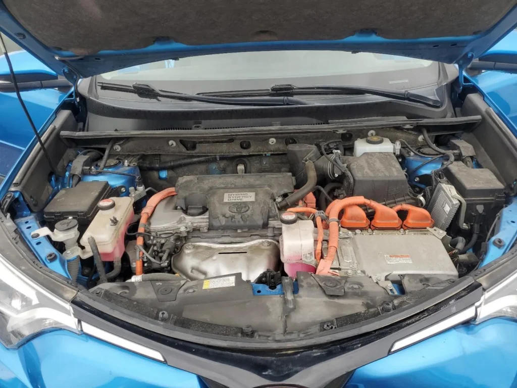 Komora silnika Toyota RAV4 Hybrid: jednostka benzynowa z osprzętem hybrydowym, pomarańczowe przewody wysokiego napięcia.