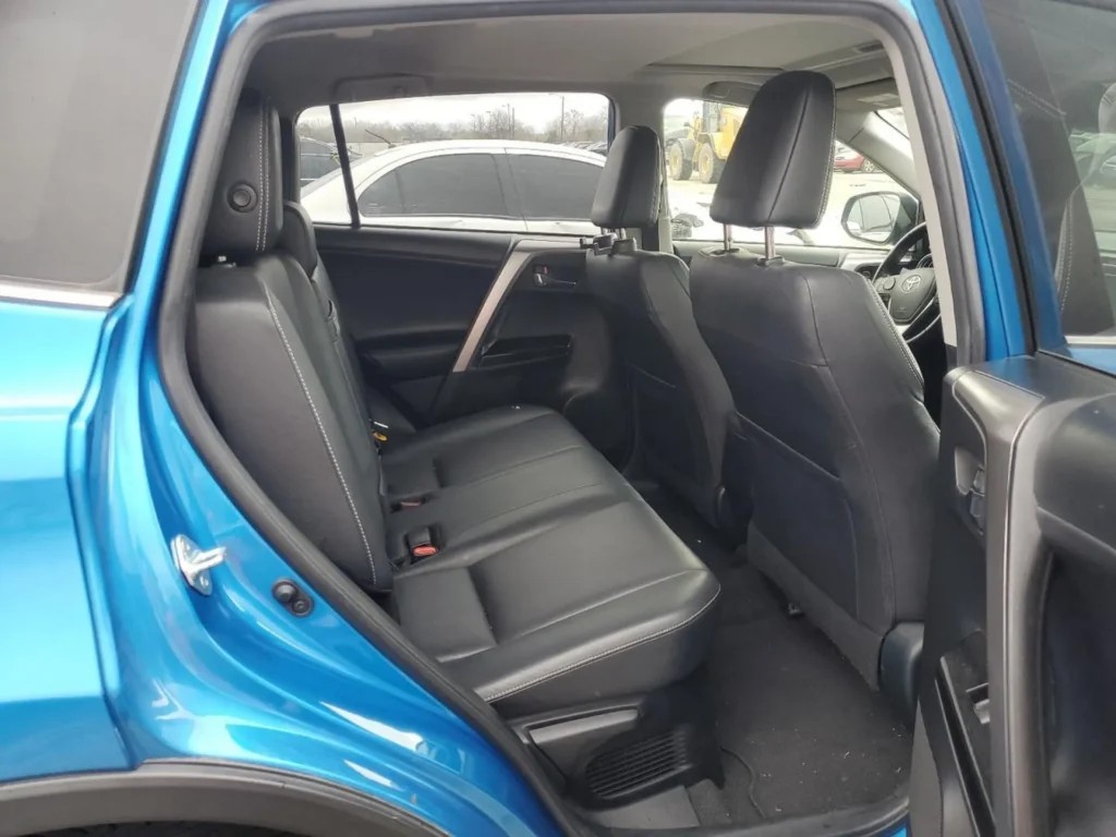 Tylna kanapa Toyota RAV4: trzy miejsca w czarnej skórze, otwarte tylne drzwi, widoczne nawiewy i przestrzeń na nogi.