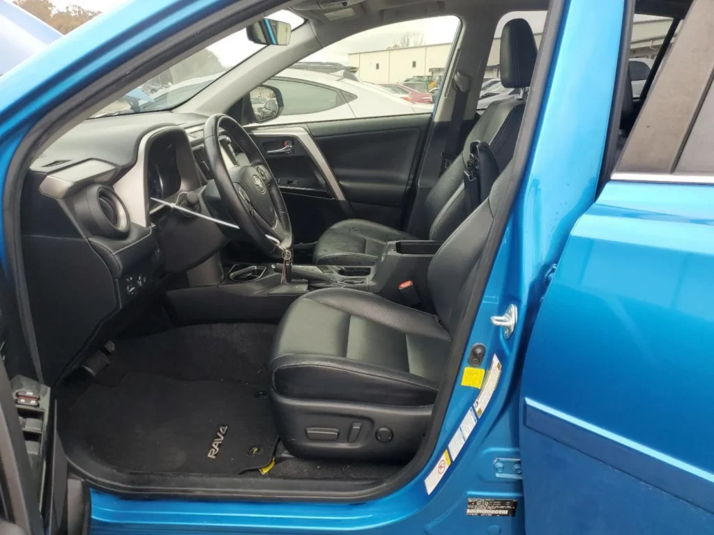 Wnętrze kierowcy Toyota RAV4: czarna skórzana kanapa, kierownica wielofunkcyjna, konsola środkowa.