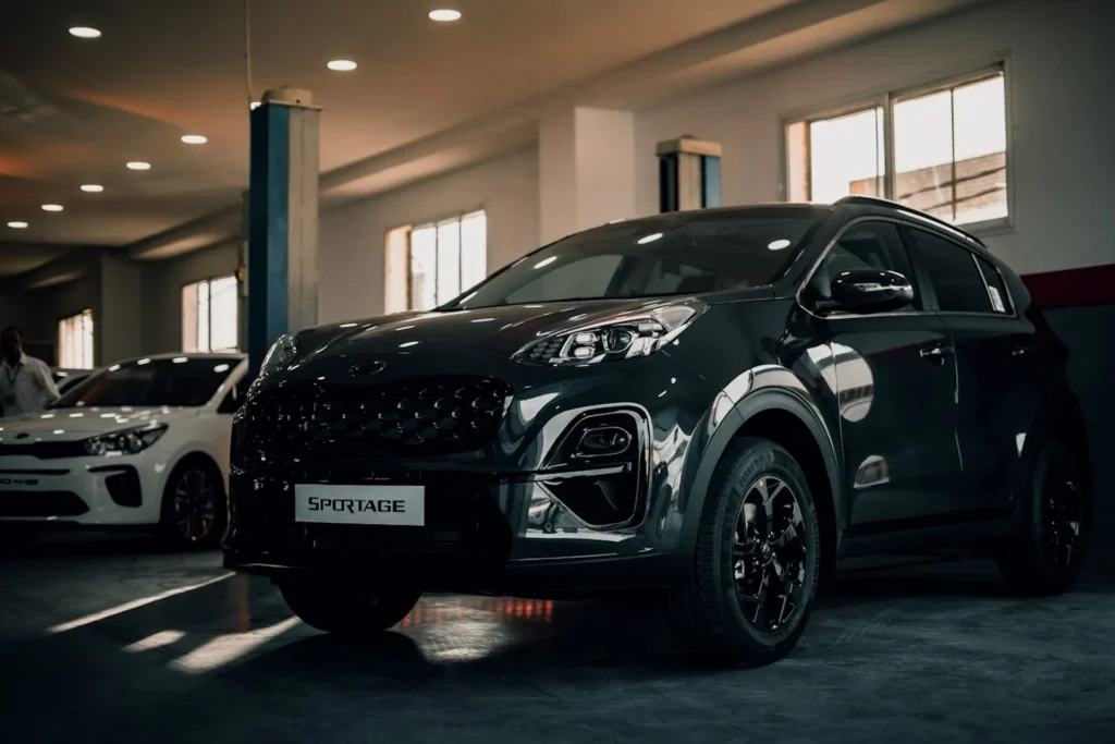 Czarny SUV Kia Sportage zaparkowany w oświetlonym salonie samochodowym