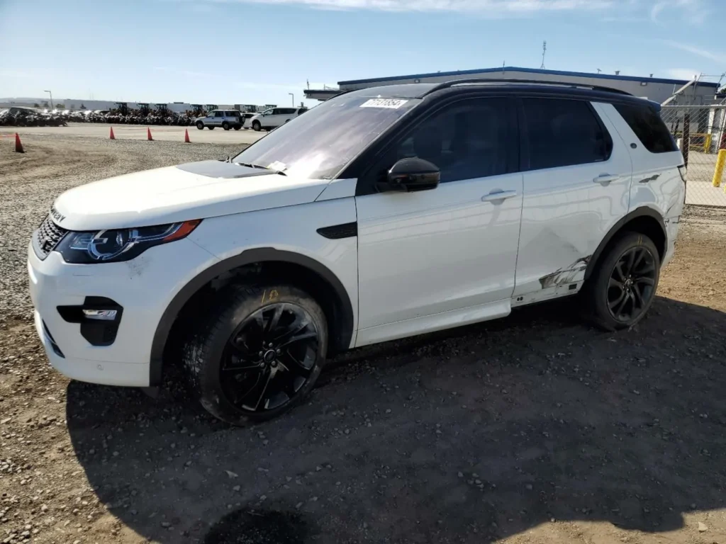 Biały Land Rover Discovery Sport, widok z prawego przodu, czarny dach; auto na żwirowym placu.