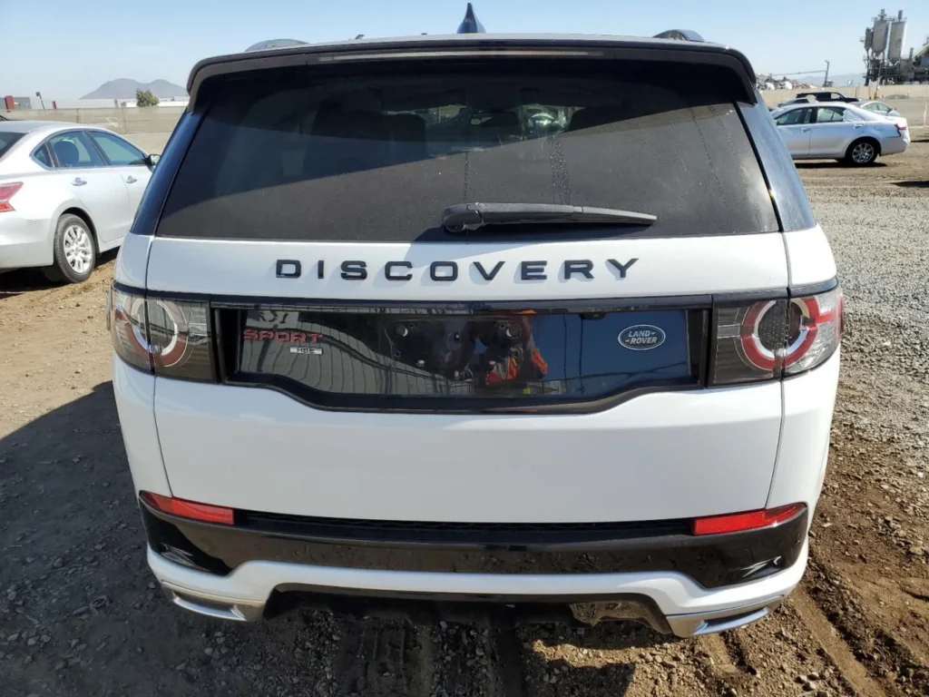 Tył Discovery Sport w bieli, czarne wstawki lamp, napis DISCOVERY na klapie.