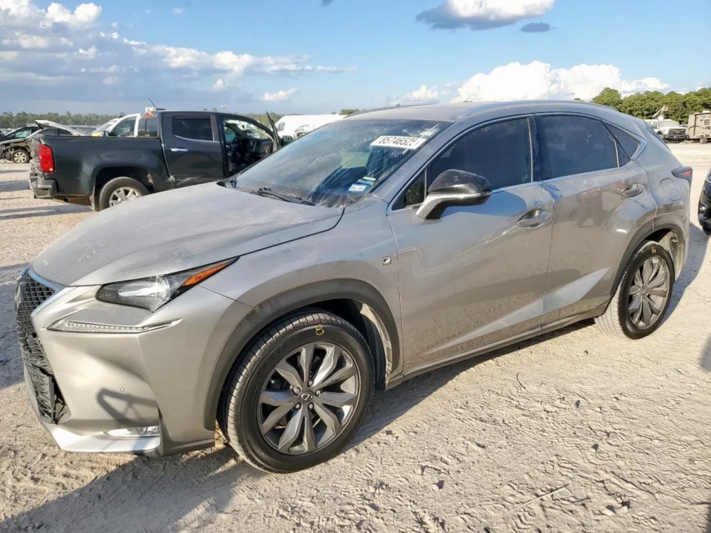Szary Lexus NX (F Sport) z lewej strony, na żwirowym placu, delikatnie zakurzony.