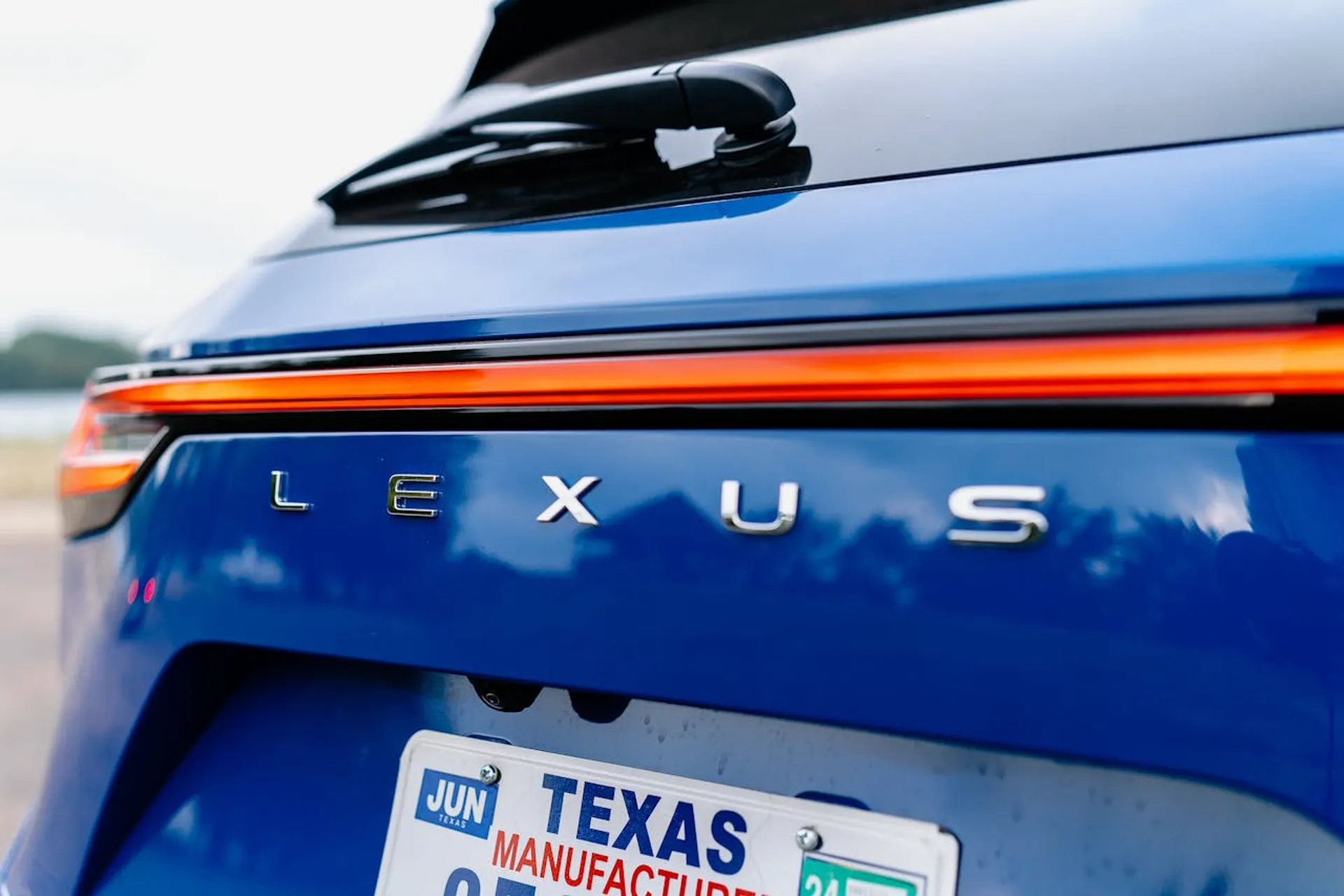 Tył niebieskiego Lexusa z zapalonymi pomarańczowymi światłami i teksańską tablicą rejestracyjną