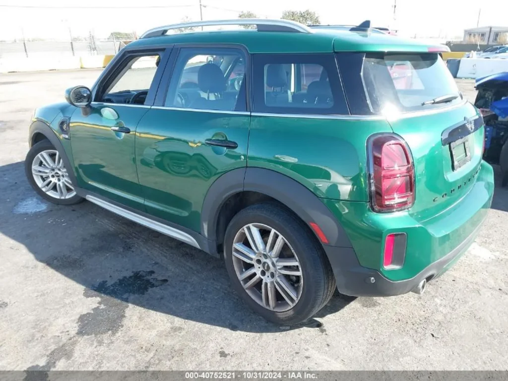 Tył-lewy zielonego Mini Countryman, auto na słońcu na placu.