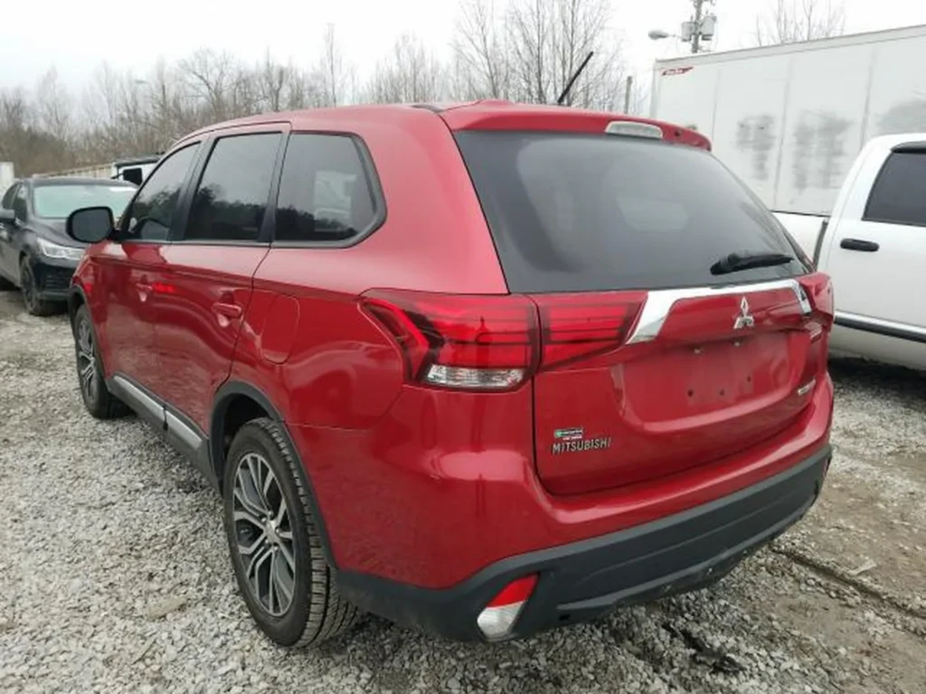 Tył czerwonego Mitsubishi Outlandera, widok z lewej strony, samochód zaparkowany na placu.