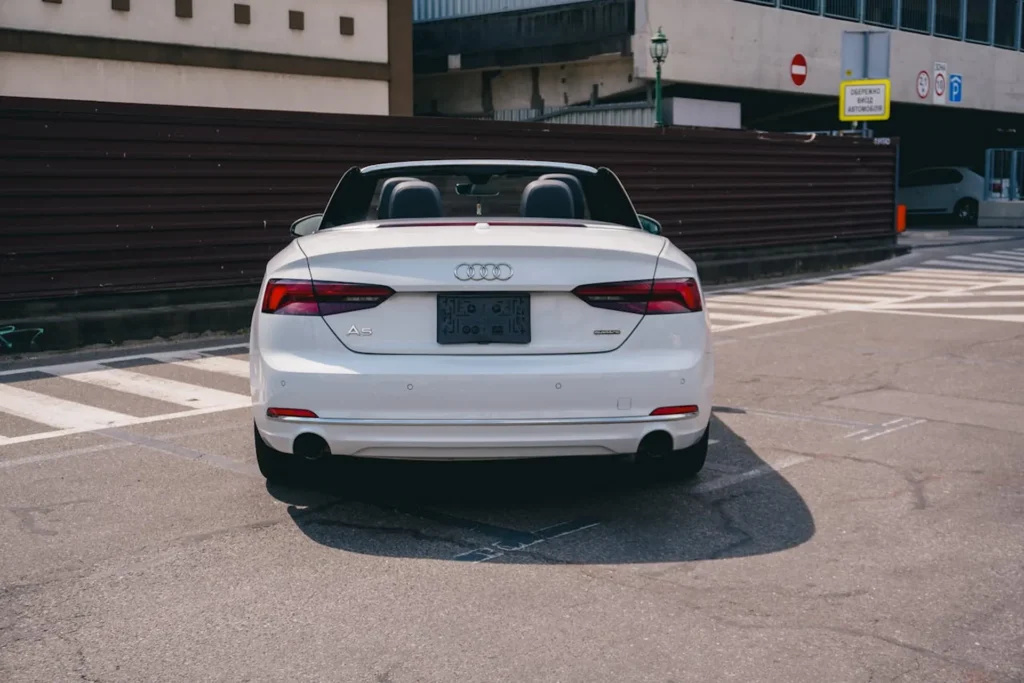 Białe Audi A5 Cabrio widziane od tyłu na miejskim parkingu.