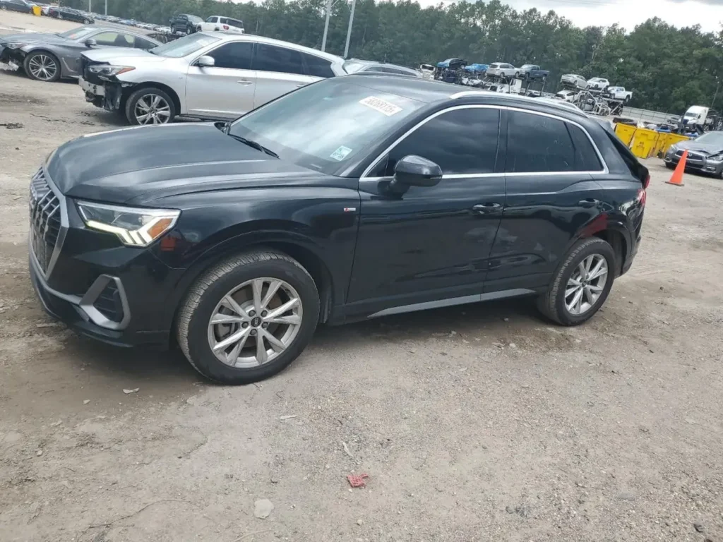 Czarne Audi Q3 na parkingu z innymi autami w tle, ujęcie z przodu pod kątem