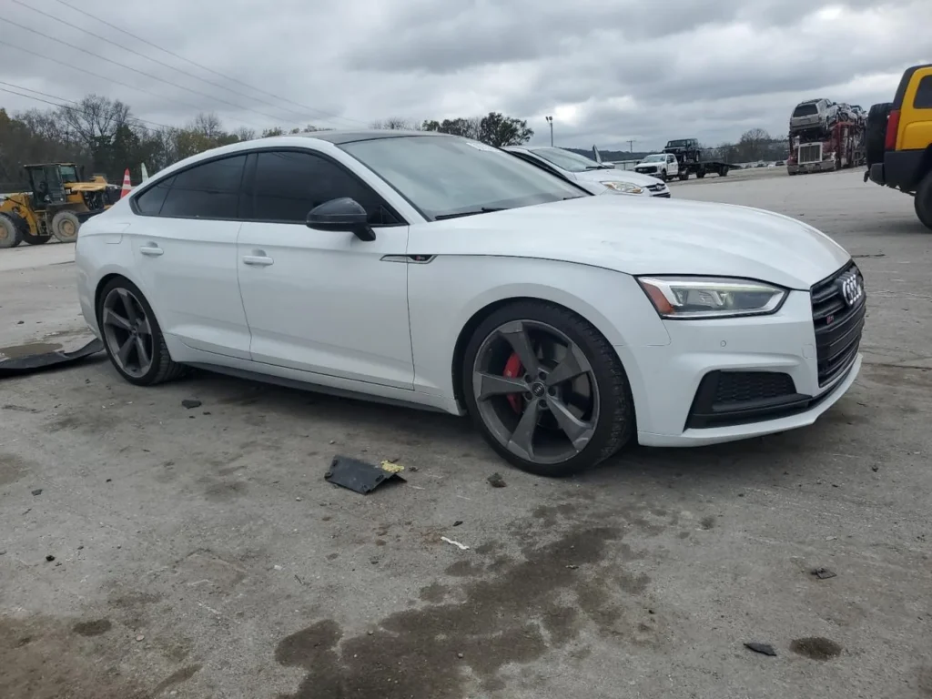 Białe Audi S5 Sportback na ciemnych felgach widziane z boku na placu aukcyjnym