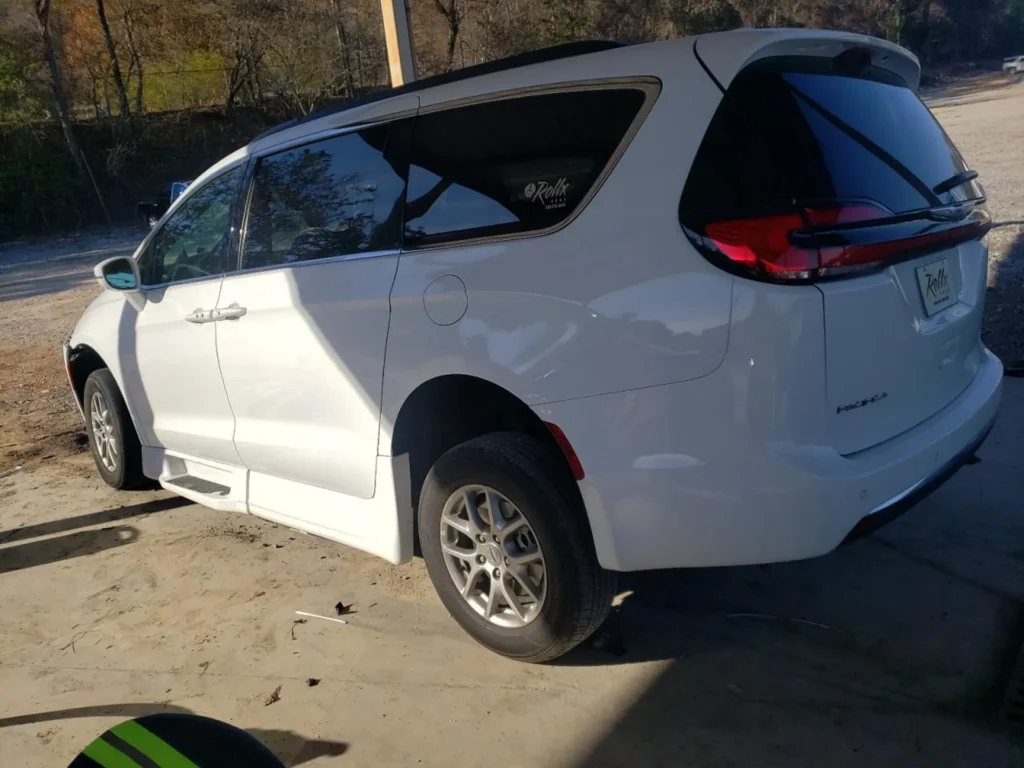 Biały Chrysler Pacifica z obniżoną boczną zabudową, widoczny z boku i tyłu na zadaszonym placu