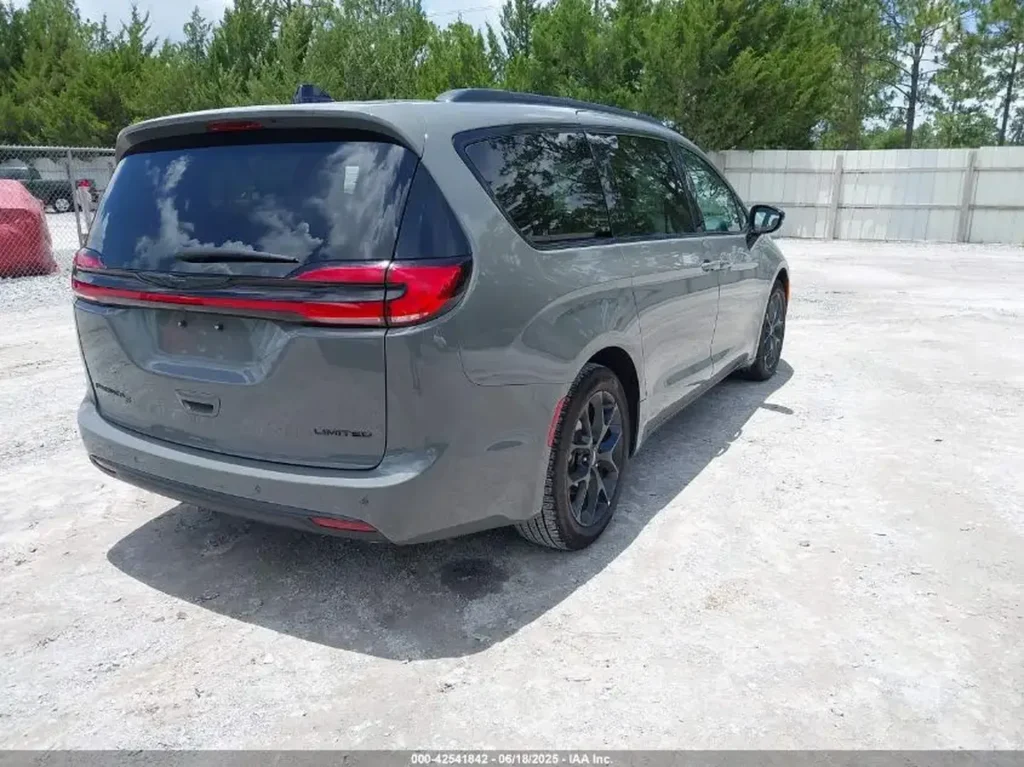 Szary Chrysler Pacifica Limited po liftingu, widok z tyłu i boku, zaparkowany na żwirowym placu.