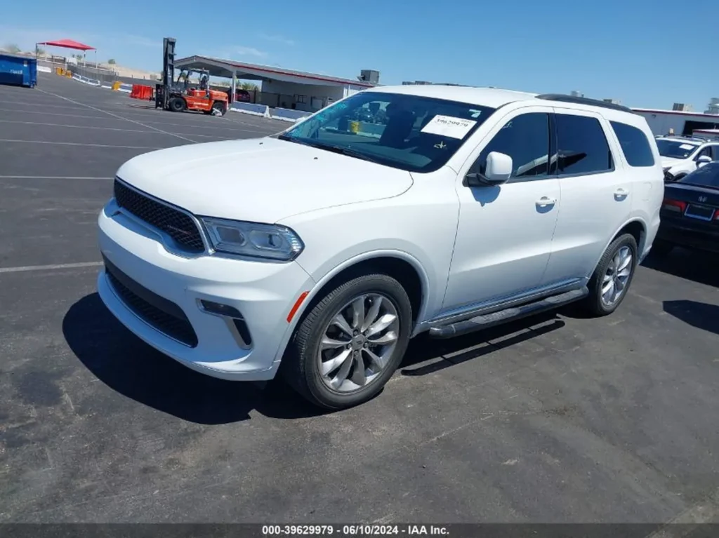 Biały Dodge Durango z przodu i z lewej strony, zaparkowany na pustym asfaltowym parkingu.