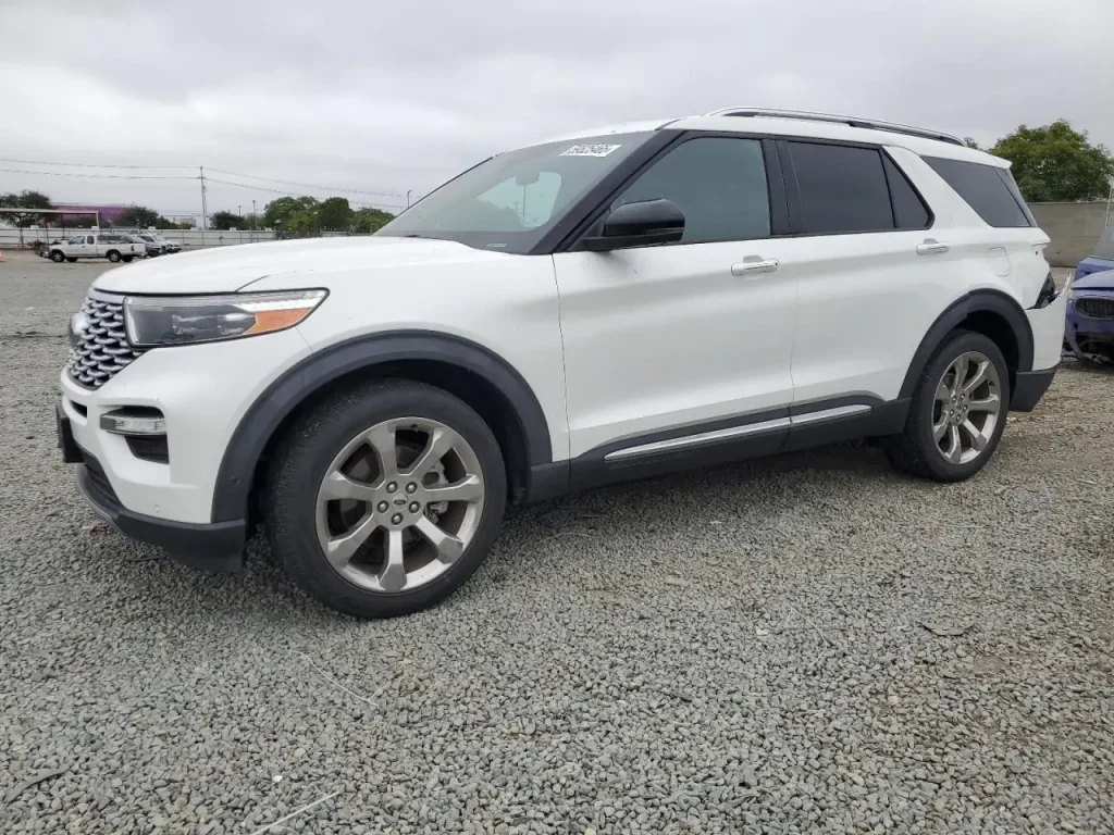 Biały Ford Explorer SUV, widok z przodu i boku na żwirowym parkingu.