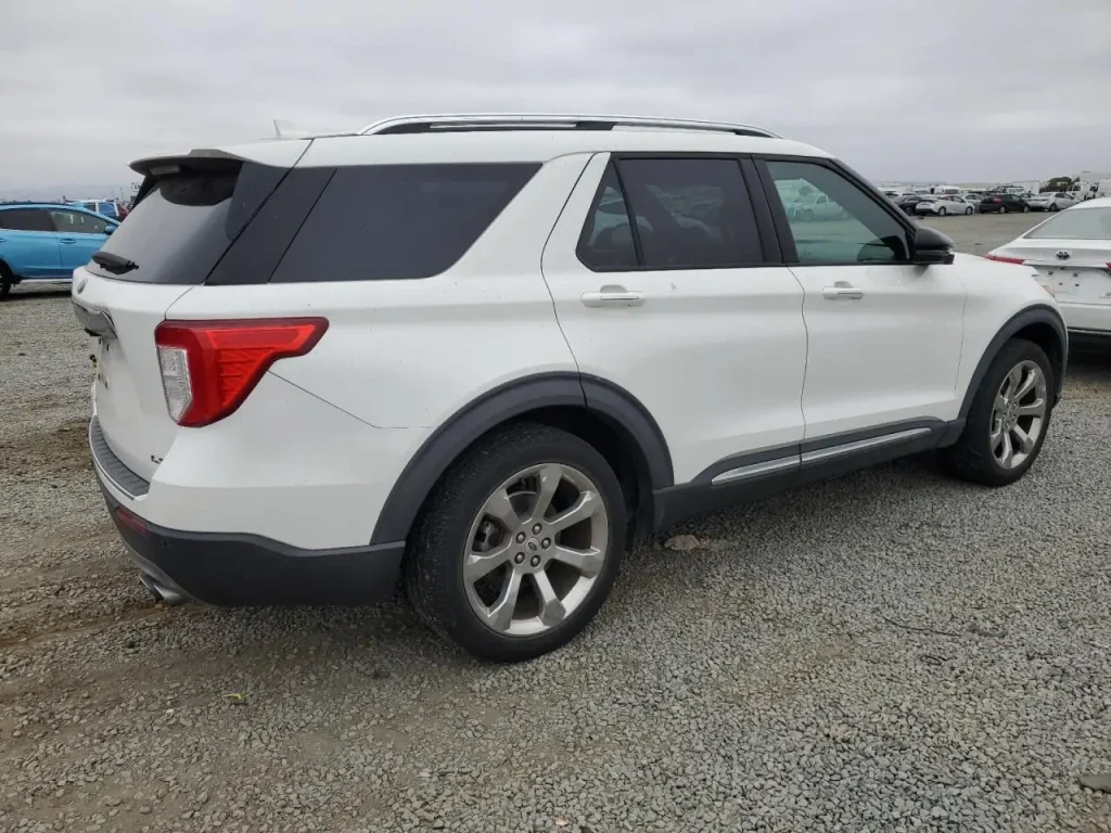 Biały Ford Explorer widoczny z tyłu i boku, zaparkowany na żwirowym parkingu.
