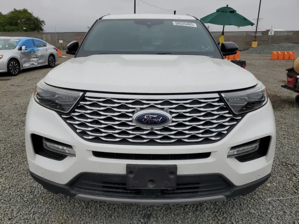 Przód białego Forda Explorera z dużym chromowanym grillem, zaparkowany na żwirze.