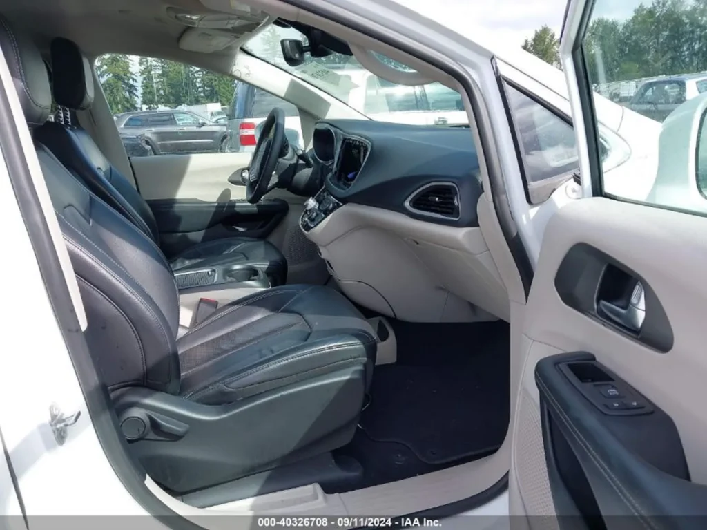Wnętrze Chryslera Pacifica z czarnymi skórzanymi fotelami, widok z otwartych przednich drzwi kierowcy.