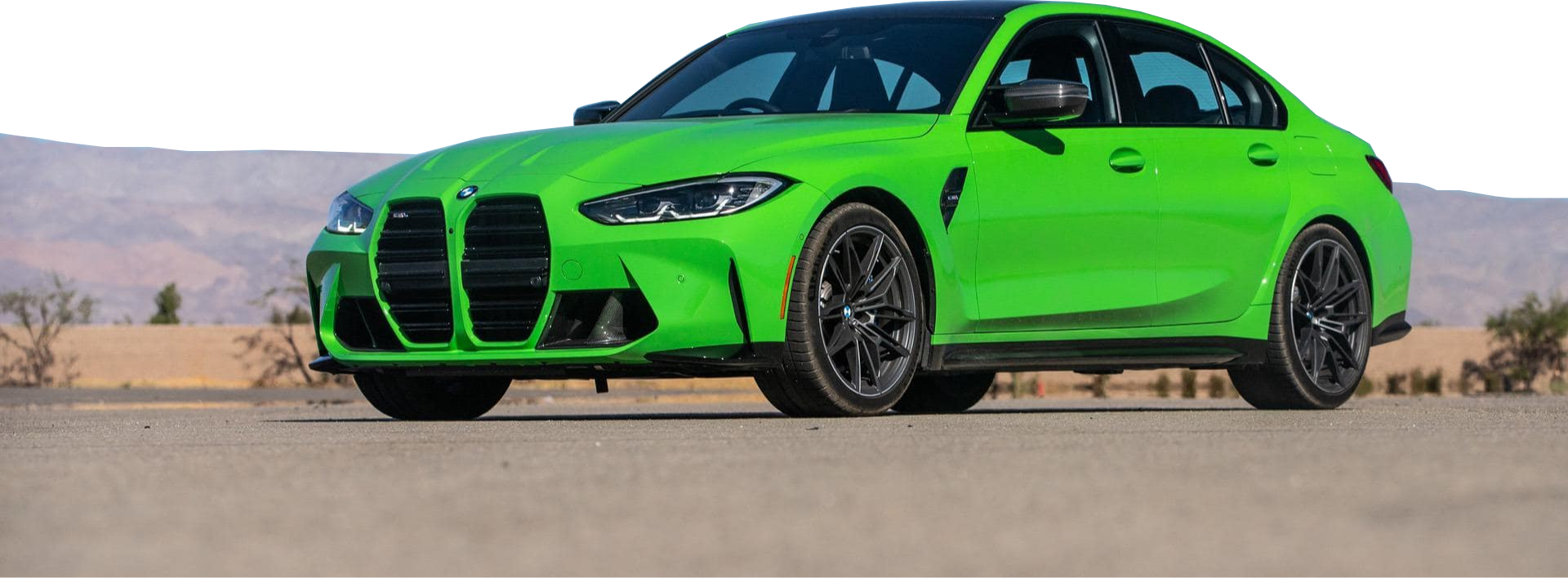 Zielone BMW M3 stoi na pustynnej drodze z górami w tle