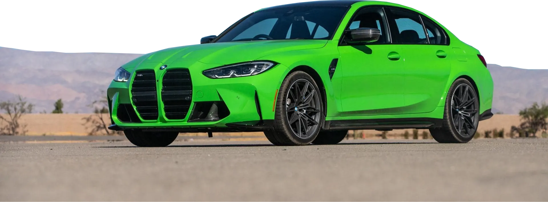Zielone BMW M3 stoi na pustynnej drodze z górami w tle
