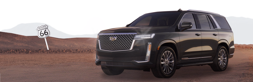 Ciemny Cadillac Escalade na pustynnej drodze obok znaku Route 66